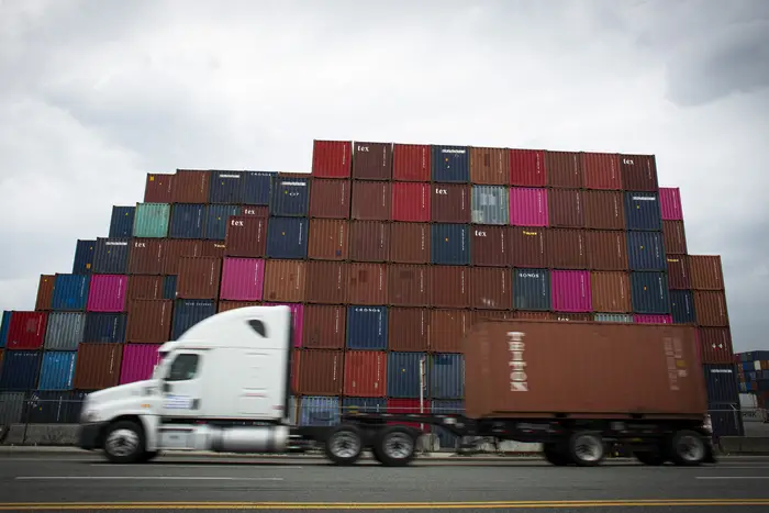 A truck drives by containers at a port.